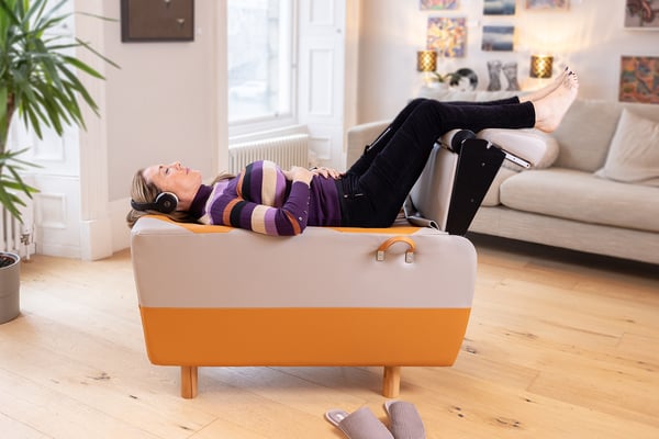 adult woman in her 40s enjoying a BackHug treatment session, lying down on the BackHug device with the legs in a tabletop position