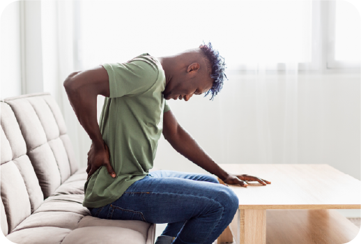 Man holding back in pain while sitting